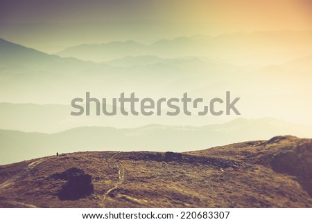 Misty autumn mountain hills landscape. A lone traveler walking along the trail.Filtered image:cross processed vintage effect.