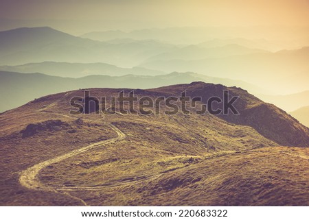 Misty autumn mountain hills landscape. A lone traveler walking along the trail.Filtered image:cross processed vintage effect.