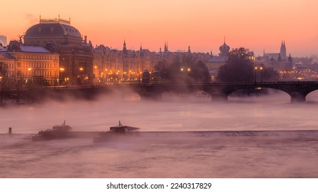 A misty dawn in the winter morning over Vltava river and national theatre in Prague. 