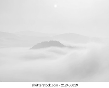 Misty Dreamy Landscape. Deep Misty Valley In Autumn Park Full Of Heavy Clouds Of Dense Fog. Sandstone Peaks Increased From Foggy Background. Black And White Picture. 