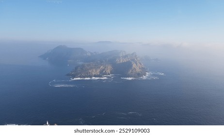 Misty horizon, Blue ocean, Rocky island, Foggy atmosphere, Soft waves, Hidden coastline, Serene waters, Isolated rock formation, Calm seascape, Distant island, Gentle mist, Tranquil view, Peaceful - Powered by Shutterstock