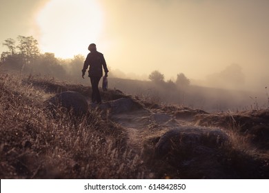 A misty morning by the lake.  Silhouette of man walking away. Space for text. - Powered by Shutterstock