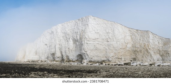 Misty morning in Hope Gap beach, Cuckmere Haven, located between Seaford and Eastbourne. Panorama. Pebbly coastline with seaweed and the white cliffs on the background, selective focus - Powered by Shutterstock