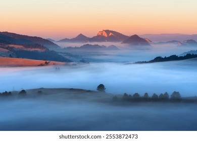 Misty morning landscape with rolling hills and distant mountains under a soft sunrise light - Powered by Shutterstock