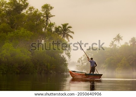 Misty morning and a man, fisherman on the boat on ethe river with 
