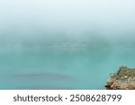 Misty morning at a tranquil Lake Haiyaha with calm turquoise waters and a rocky shore under a blanket of fog