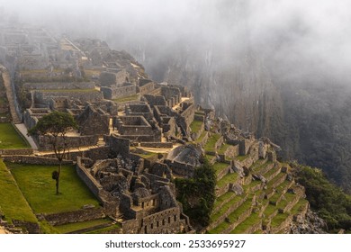 A misty morning view of Machu Picchu, the ancient Incan city in the Andes Mountains of Peru, with terraced fields and stone structures. - Powered by Shutterstock