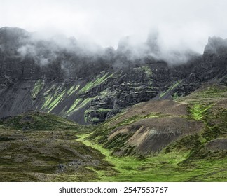 Misty mountain landscape with lush green slopes and rugged cliffs under a cloudy sky. - Powered by Shutterstock