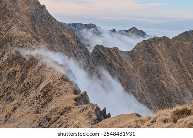 Misty mountain peaks shrouded in clouds. Dramatic landscape photography showcasing rugged terrain and atmospheric conditions. Ideal for travel, nature, or adventure themes. - Powered by Shutterstock