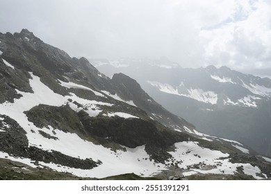 Misty mountain range with patches of snow. - Powered by Shutterstock