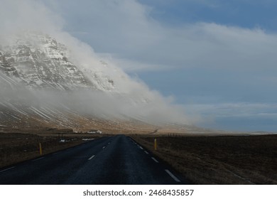 Misty mountain road with fog rolling over snow-covered peaks - Powered by Shutterstock