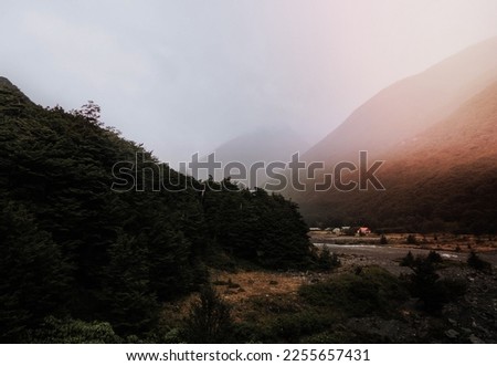 misty mountain valley and a huddle of woodland huts
