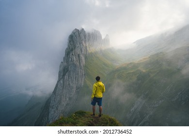 Misty Nature. Hiker In Yellow Stand On Peak In Rock And Watching Over The Misty And Foggy Morning Valley To Sun. 