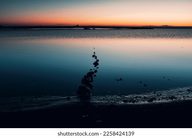 Misty seascape - calm water surface of the lake reflects lilac sky with pink and blue clouds after sunset. White nights season in the Republic of Karelia, Russia. Blur filter, space for copy.