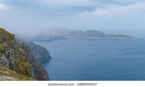 A misty view from the clifftops overlooking the dramatic coastline of Northern Norway. Nordkap or North Cape