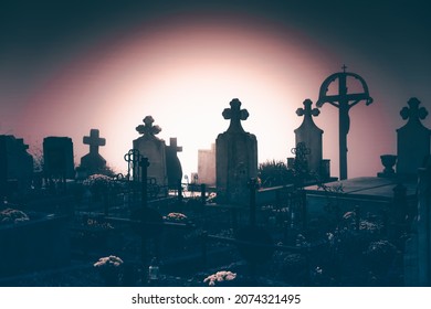 Misty view of dark stone crosses and tombstones in a deserted graveyard. Halloween concept