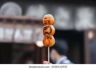 Mitarashi Dango skewer on woman hand, Its a Japanese rice dumpling and sweet made from mochi, Famous of street food in Japan - Powered by Shutterstock