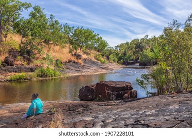 Mitchell Plateau, WA, Australia - May31, 2015: An Indigenous Australian Woman From The Local Kandiwal Community Sits Beside A Prisitne Outback River.