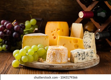 Mix cheese on wooden board with grapes. Front view.