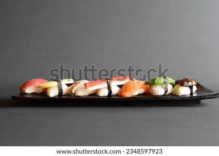 A mix of colorful sushi nigiri with rice and nori. Nigiri tuna, mango, shrimp, shrimp stick, salmon, avocado and shitake mushroom. Japanese food
