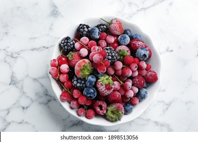 Mix Of Different Frozen Berries In Bowl On White Marble Table, Top View