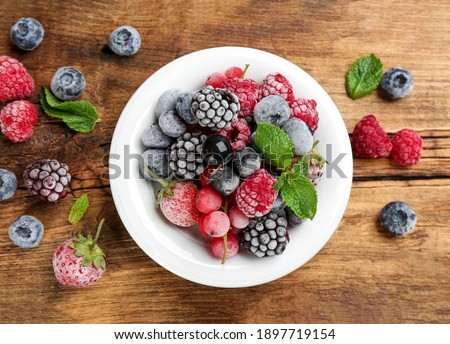 Mix of different frozen berries on wooden table, flat lay