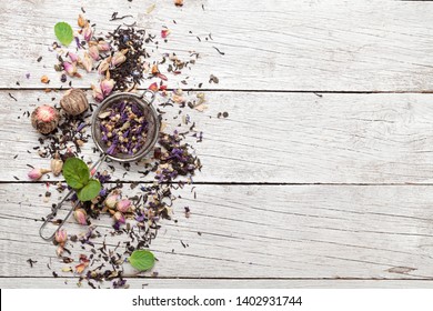 Mix of different herbal and fruit dry teas on wooden table. Top view flat lay with copy space