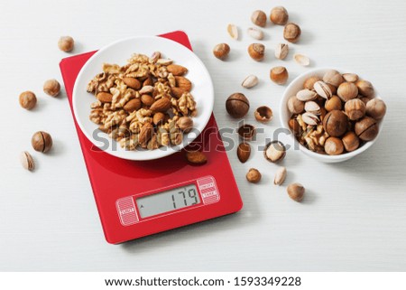 mix of different nuts on  kitchen scale on a white table