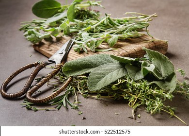 Mix of fresh Italian herbs from garden on an old table. Rosemary, temyan, oregano. Dark background
