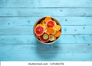 Mix Of Fresh Ripe Citrus Fruits, Cutted Into Slices In A Bowl On A Blue Wooden Background With Copyspace. Top View Of Red Oranges, Mandarines, Lemons, Lomes And Grapefruits Chopped In Big Bowl.