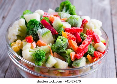 Mix of frozen vegetables in glass on wooden table