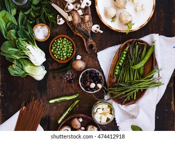 Mix green ingredients. Composition ingredients with mushroom, asparagus, green beans, olive, tofu cheese, bok choy, zucchini and fresh herbs on a dark table. - Shutterstock ID 474412918