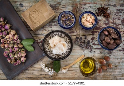 Mix of herbs, flower, argan nut and oil, shea nuts and butter, anise and Aleppo soap on wooden table