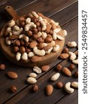 mix of nuts from almonds, walnuts, cashews, peanuts on a wooden plate close up view