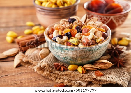 Mix of nuts and dried fruits on a old rustic table. Gold pistachios, cashews, hazelnuts, almonds. Food background.