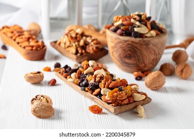 Mix of nuts and raisins on a white wooden table. Presented raisins, walnuts, hazelnuts, cashews, pecans, and almonds. - Powered by Shutterstock