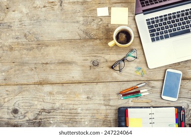 Mix of office supplies and gadgets on a wooden table background. View from above. - Shutterstock ID 247224064