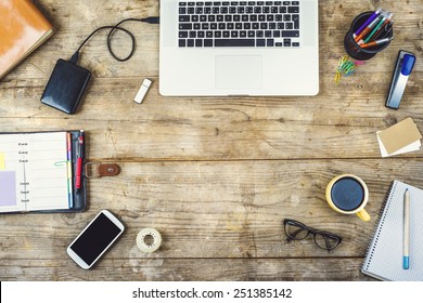 Mix Of Office Supplies And Gadgets On A Wooden Desk Background. View From Above.