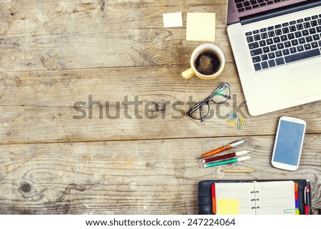 Mix of office supplies and gadgets on a wooden table background. View from above.