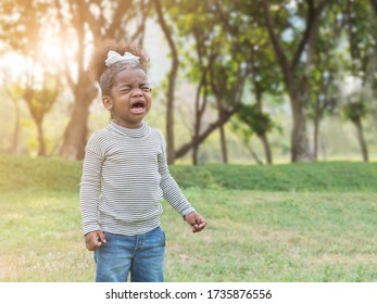 Mix race African girl crying  with copy space as blurry background of the park. Lost or throwing tantrum to mom or dad.