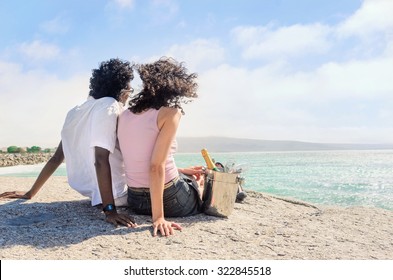 Mix race couple relaxing by the seaside, enjoying each others company on their honeymoon holiday with champagne  - Powered by Shutterstock