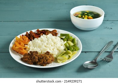 Mix Rice Is A Typical Indonesian Dish, Consisting Of White Rice And Various Side Dishes, Beef, Stir-fried Tofu, Tempeh Oreg, Sweet And Sour Chicken, Stir-fried Broccoli. Served On A Plate. 