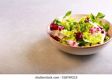 Mix salad leaves and herbs in a bowl over grey background - Shutterstock ID 518749213
