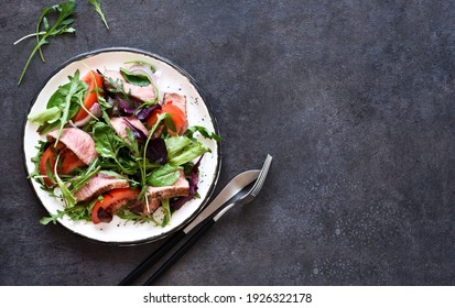 Mix Salad With Tomatoes And Medium Beef In A Plate On A Dark Background.