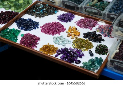 Mix shape and colorful cut mineral gemstones in jewelry market with outdoor lighting.