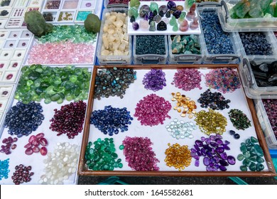 Mix shape and colorful cut mineral gemstones in jewelry market with outdoor lighting.