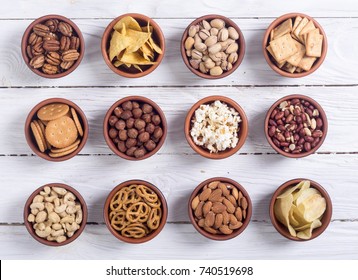 Mix of snacks : pretzels , crackers , chips , nuts and nachos