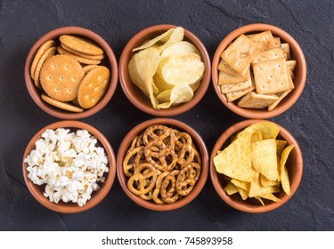 Mix of snacks : pretzels  crackers  chips  nuts  popcorn and nachos
