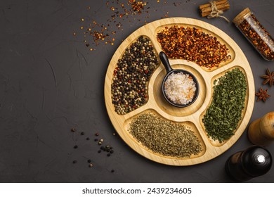 Mix spices on round wooden plate - coriander seeds, ground red pepper, salt, black pepper, rosemary, turmeric, curry. Top view, close up, gray stone background. - Powered by Shutterstock