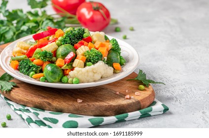 Mix of stewed vegetables in a ceramic plate on the served table. Boiled Brussels sprouts, carrots, broccoli, peas, peppers and corn. Cooked vegan or vegetarian food. - Shutterstock ID 1691185999